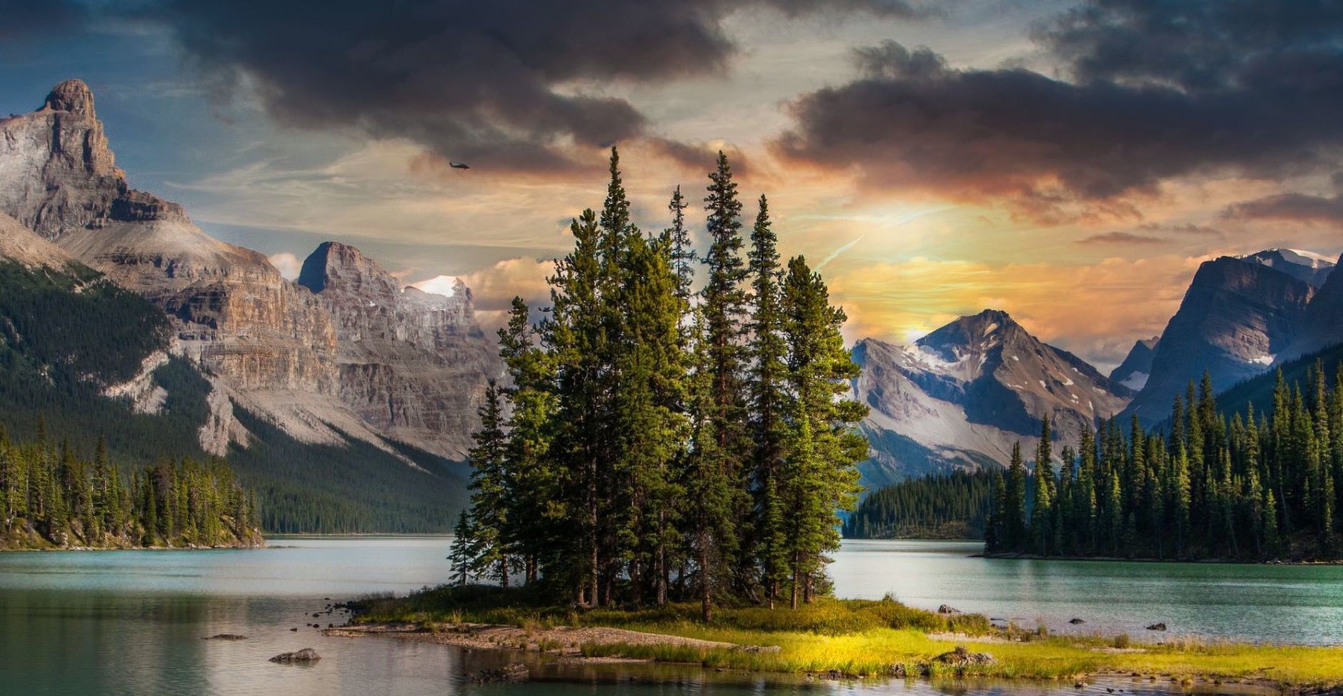 Calm mountain lake surrounded by pine forests at dusk